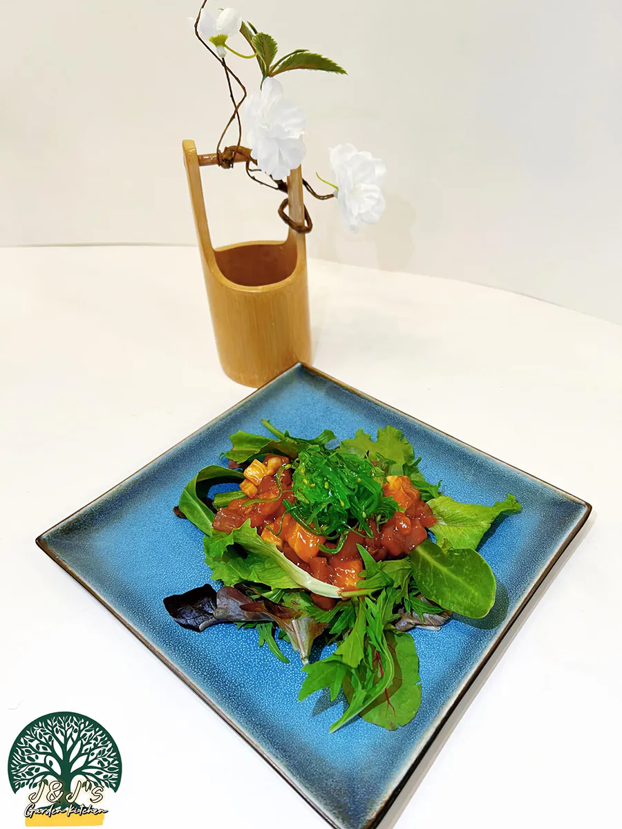 Poke bowl with marinated raw fish, seaweed salad, and mixed greens on a blue square plate at J&J's Garden Kitchen，a Asian Restaurant in Fredericksburg